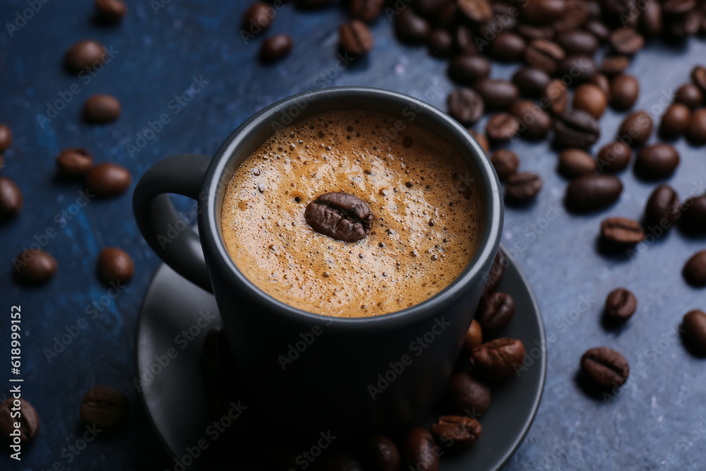 Cup of hot espresso and coffee beans on blue background