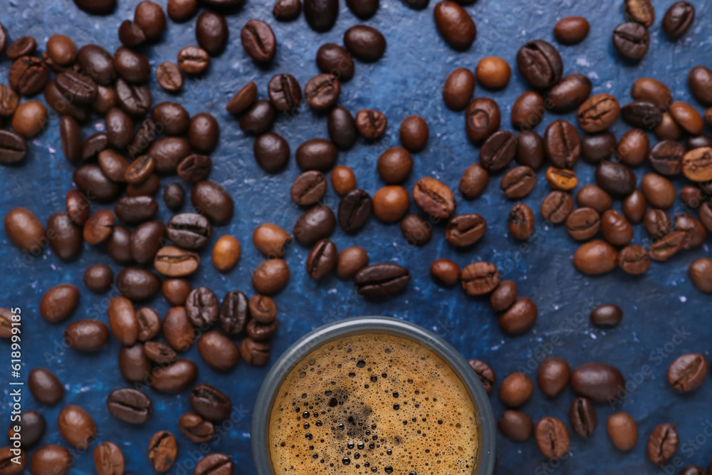 Cup of hot espresso and coffee beans on blue background