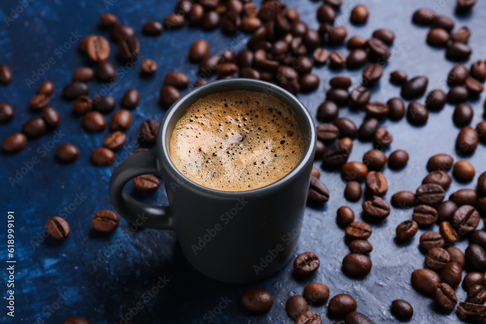 Cup of hot espresso and coffee beans on blue background