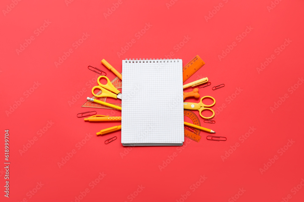 Composition with blank notebook and school stationery on red background