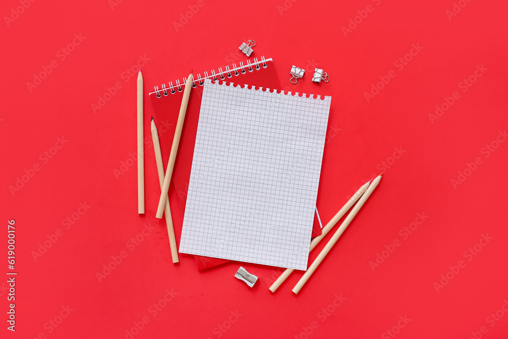 Blank notebook with different stationery on red background