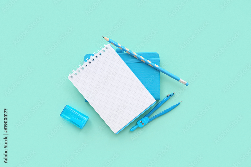 Blank notebook with different stationery on turquoise background