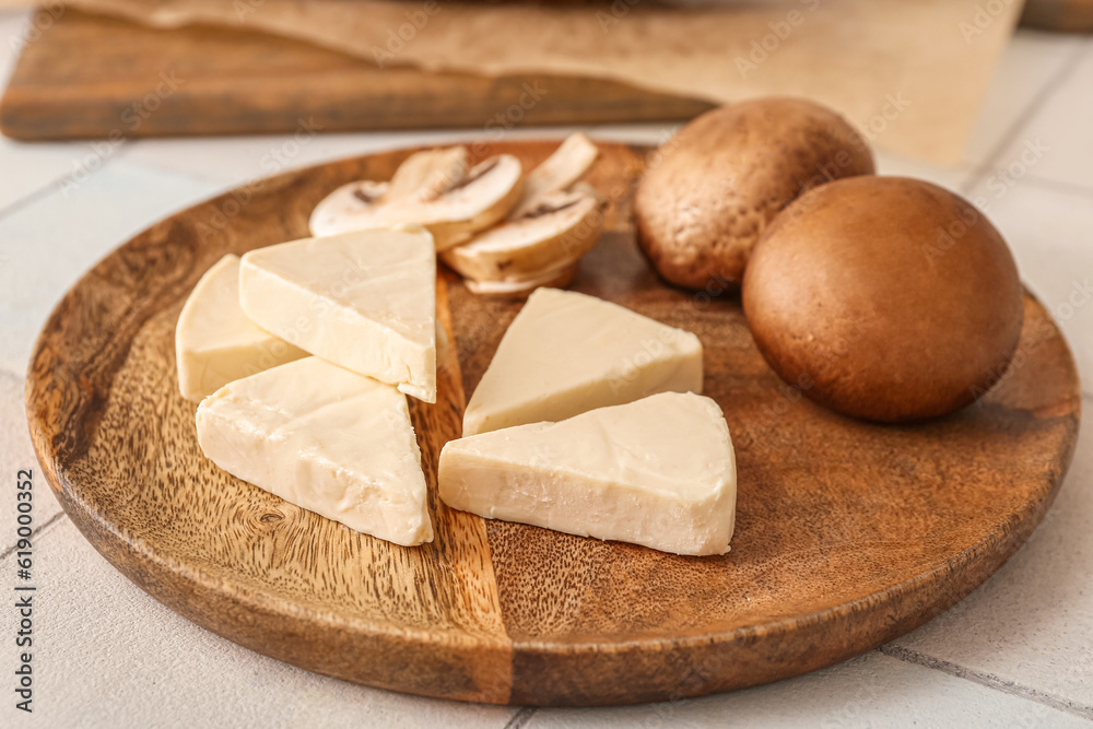 Plate with triangles of tasty processed cheese and mushrooms on light background, closeup