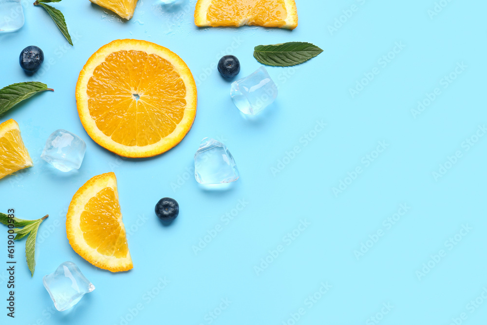 Orange slices with ice cubes, blueberries and mint on blue background