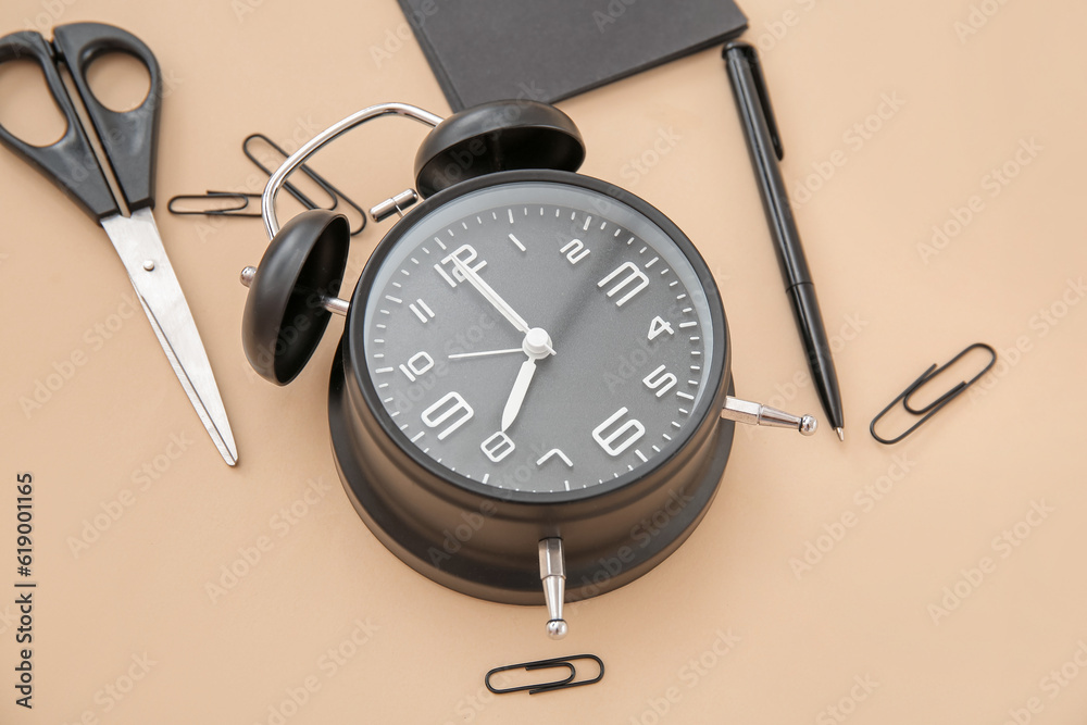 Alarm clock with different stationery on pale orange background