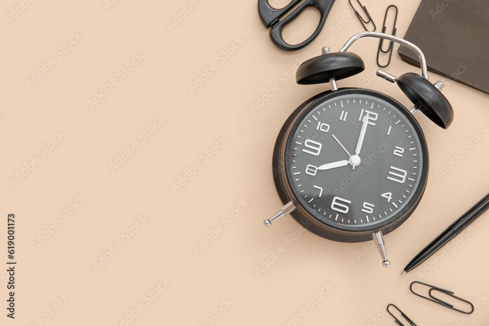 Alarm clock with different stationery on pale orange background