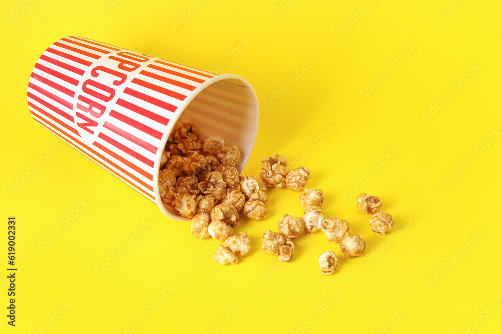 Bucket with tasty popcorn on yellow background