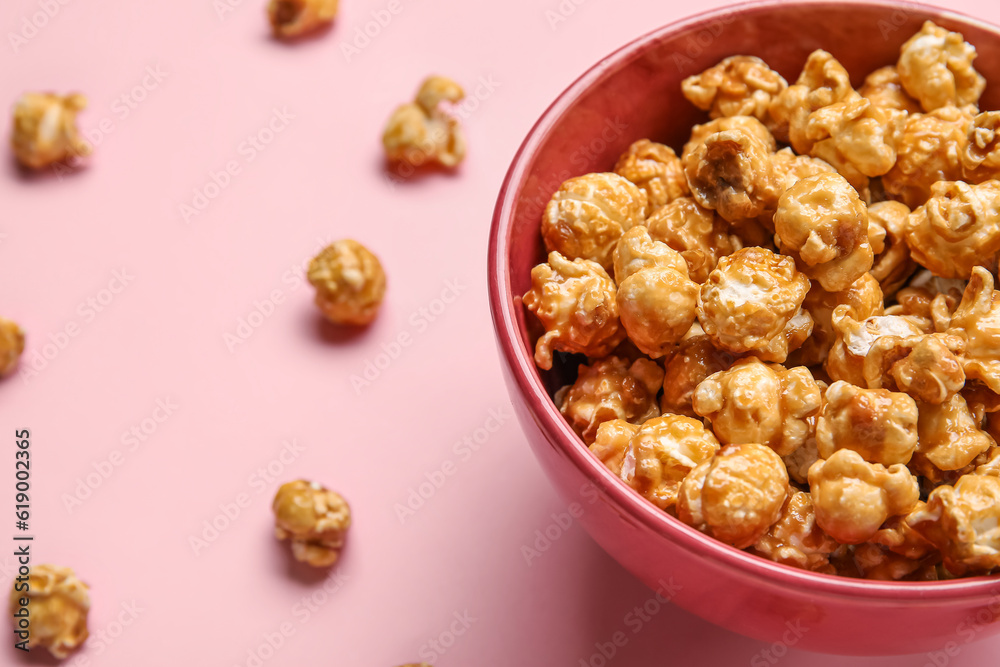 Bowl with tasty popcorn on pink background