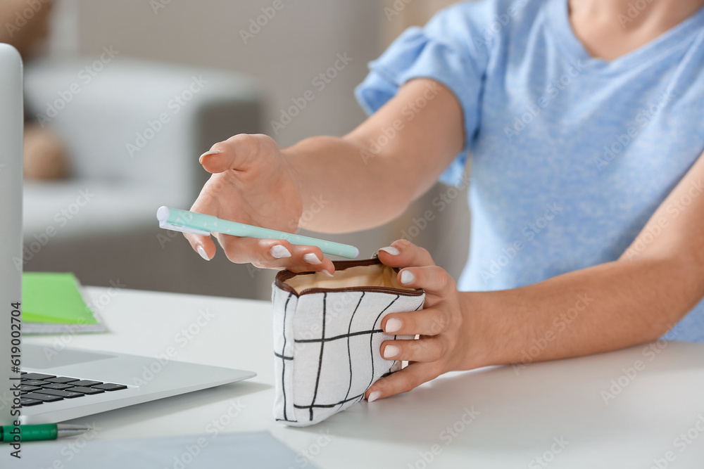 Little girl with pen and pencil case at table, closeup