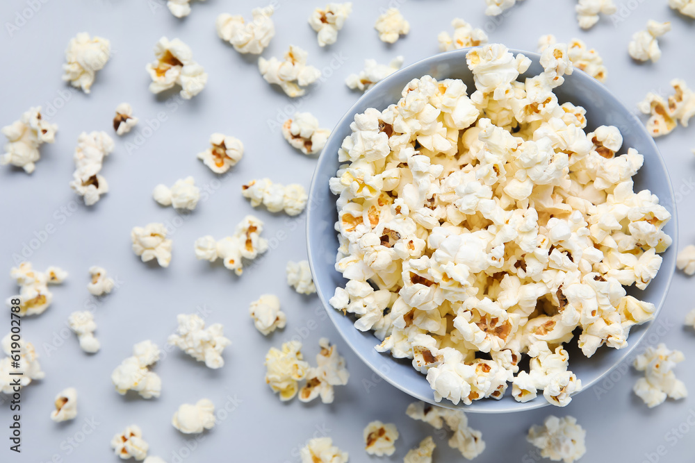 Bowl with tasty popcorn on grey background