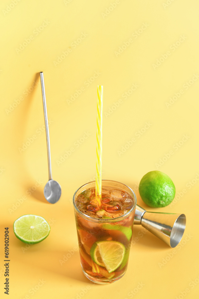 Glass of cold Cuba Libre cocktail on yellow background