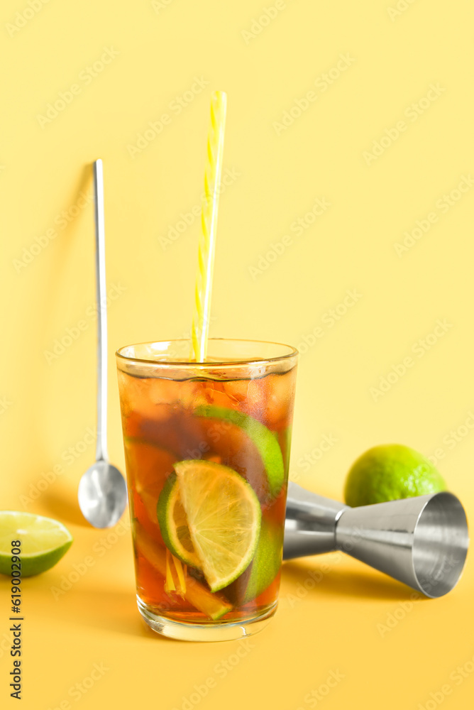 Glass of cold Cuba Libre cocktail on yellow background