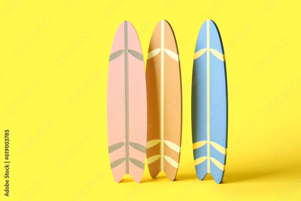 Many different colorful mini surfboards on yellow background