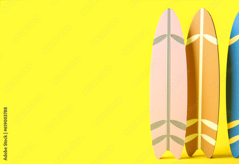 Many different colorful mini surfboards on yellow background