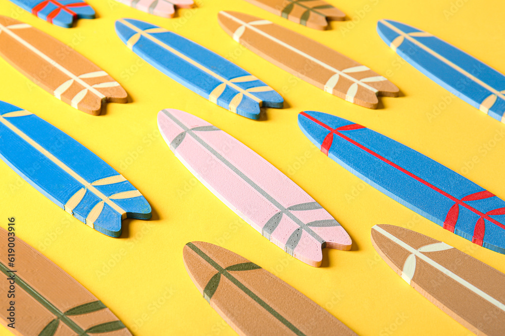 Many different colorful mini surfboards on yellow background