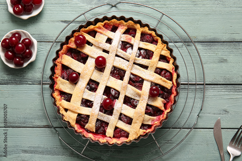 Baking dish with tasty cherry pie on blue wooden background