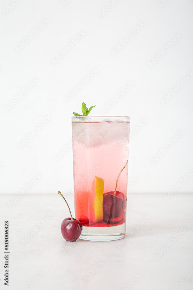 Glass of tasty cherry lemonade with lime and mint on white background