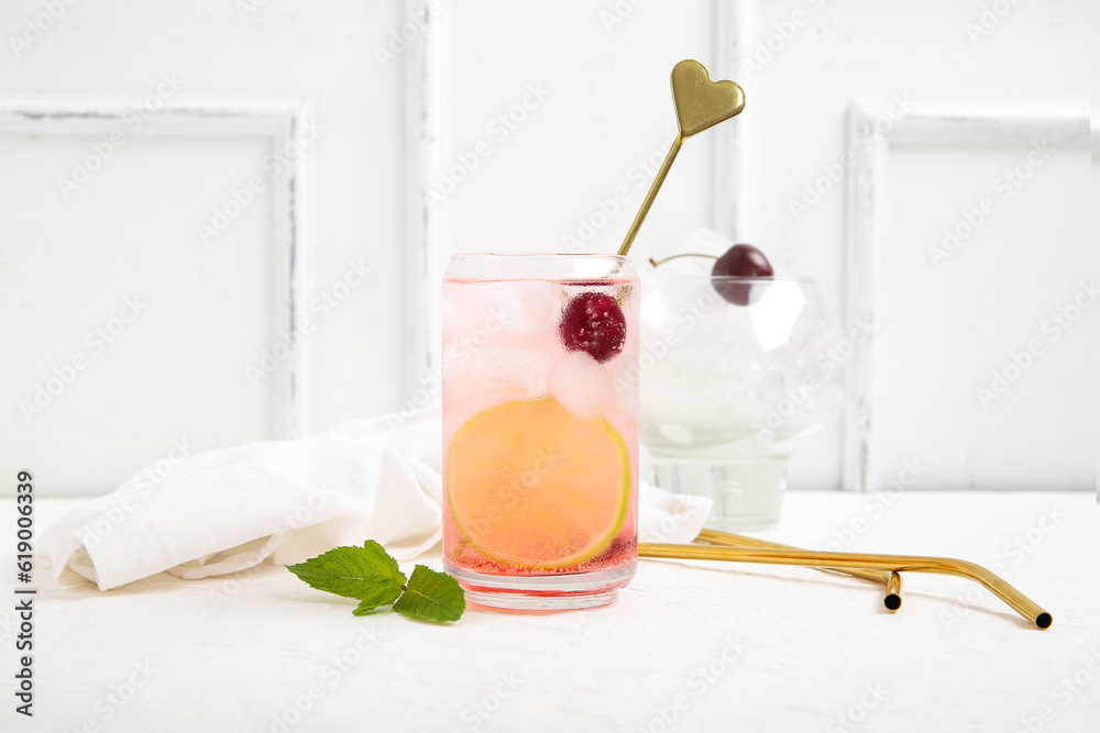 Glass of tasty cherry lemonade with lime and mint on white background