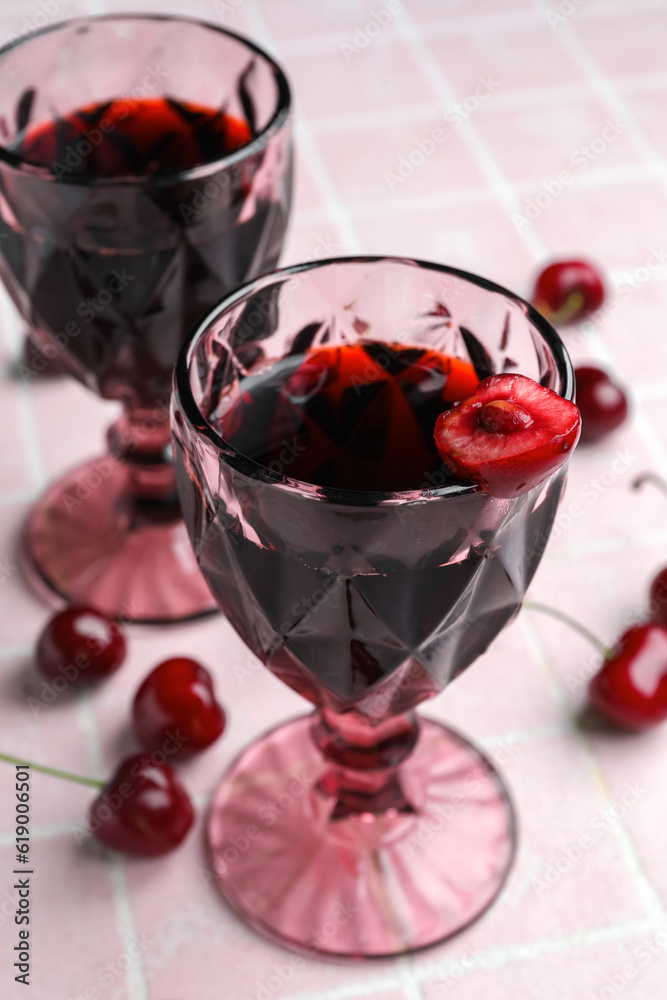 Glasses with sweet cherry liqueur on pink tile background