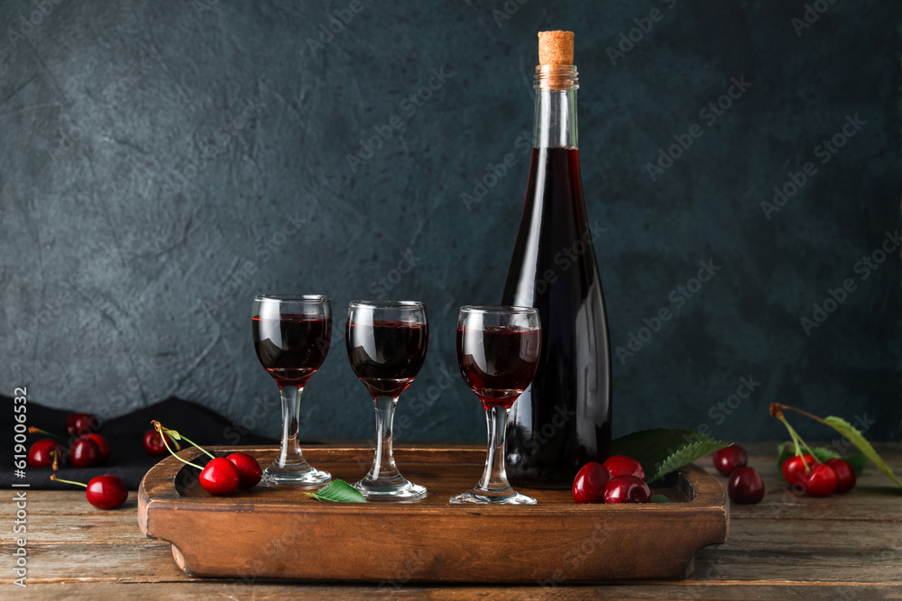 Glasses and bottle with sweet cherry liqueur on wooden table