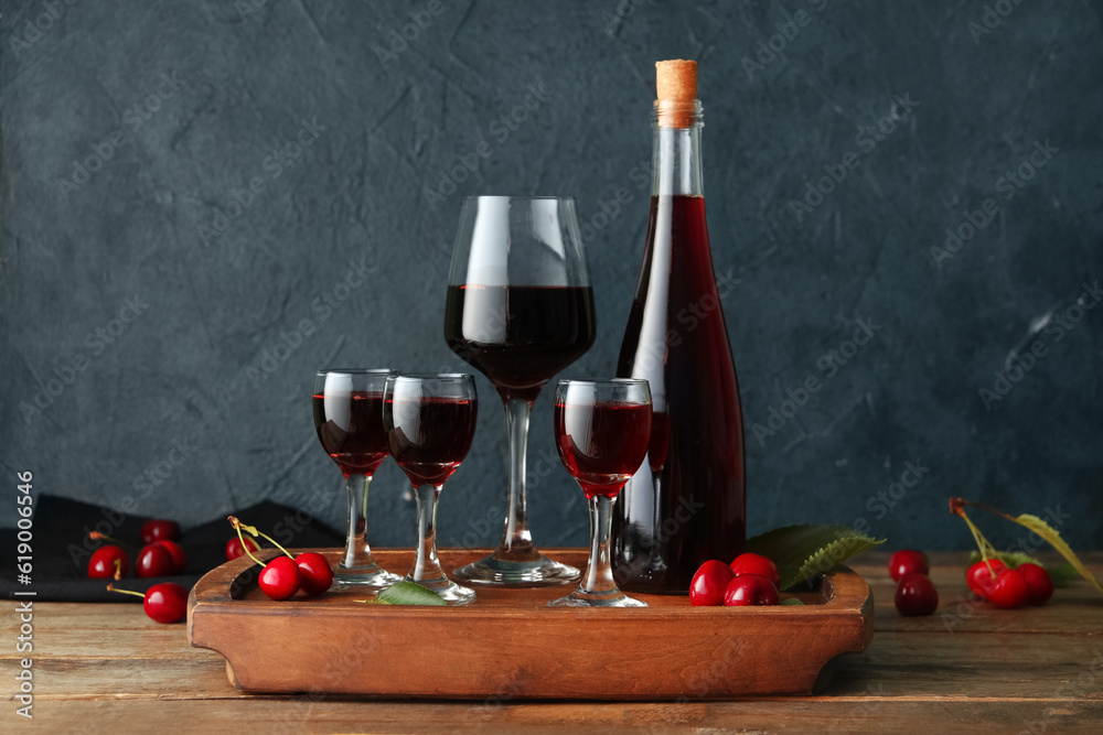 Glasses and bottle with sweet cherry liqueur on wooden table