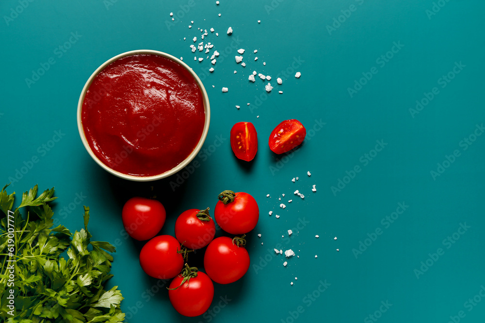 Bowl with tomato paste and fresh vegetables on blue background