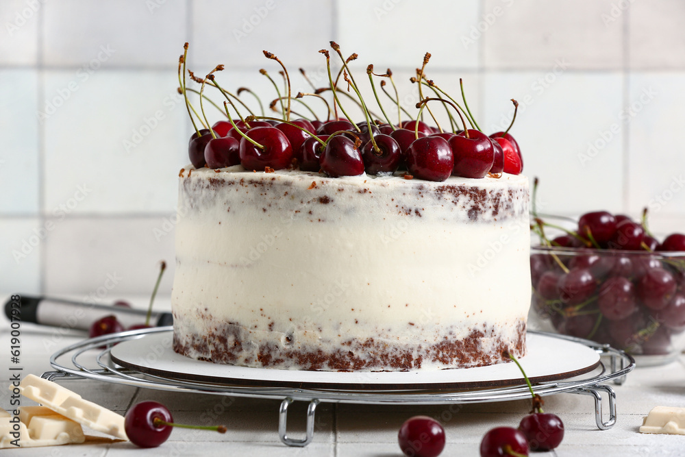 Grid with tasty cherry cake on white tile background