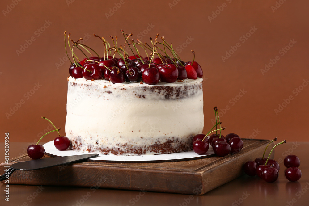 Wooden board with tasty cherry cake on red background