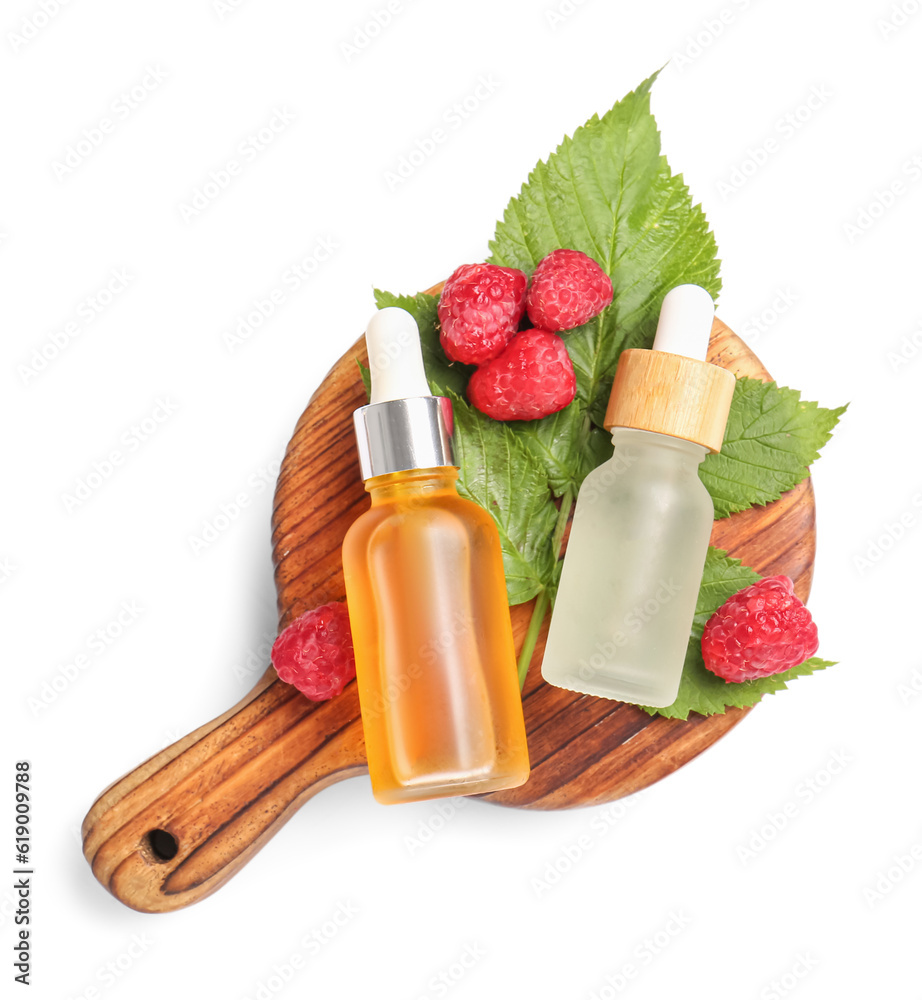 Wooden board with bottles of cosmetic raspberry oil on white background