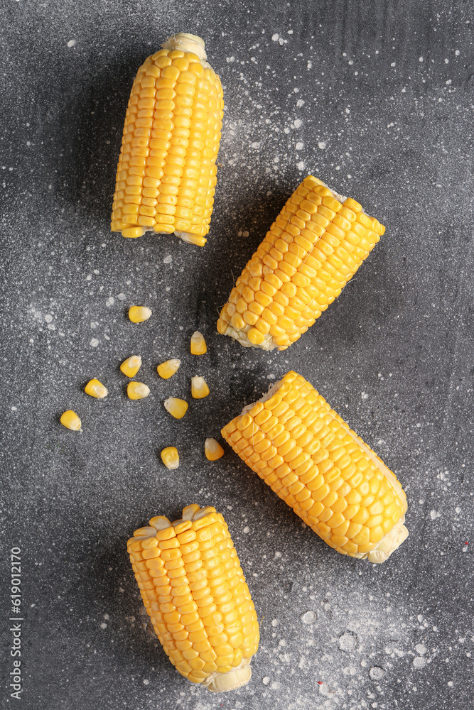 Cut fresh corn cobs and seeds on grey background