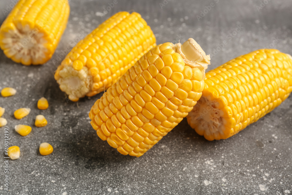 Cut fresh corn cobs and seeds on grey background