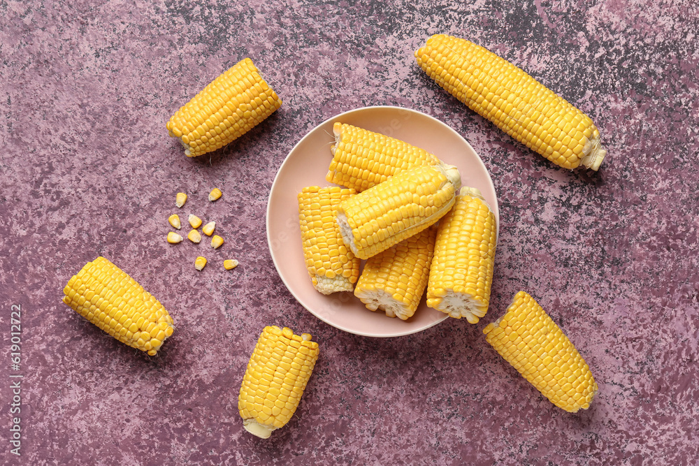 Bowl with cut fresh corn cobs and seeds on purple background