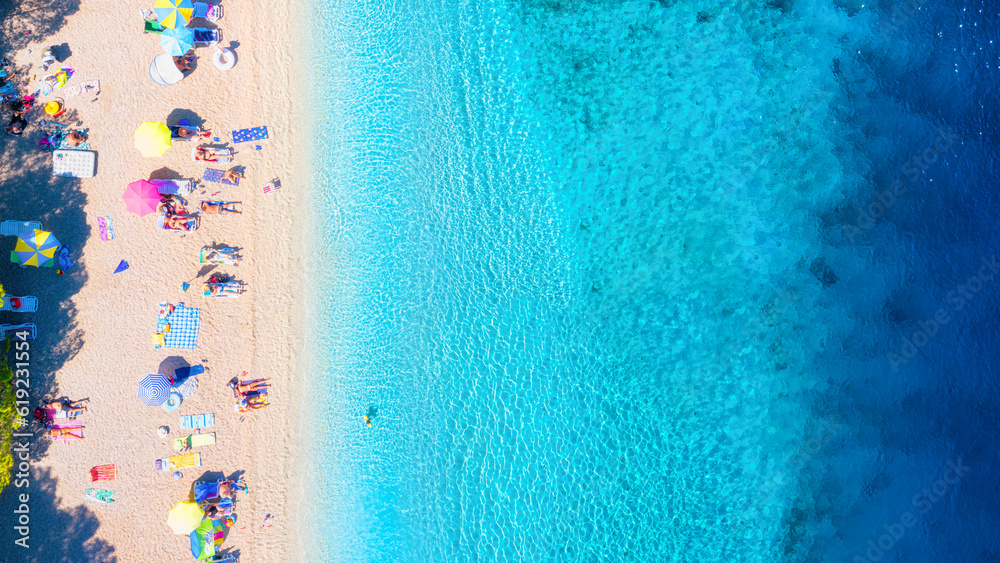 Aerial view on beach, pepole and umbrellas. Vacation and adventure. Beach and blue water. Top view f