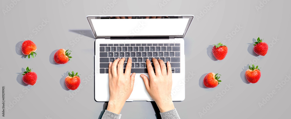 Woman using a laptop computer with fresh strawberries from above