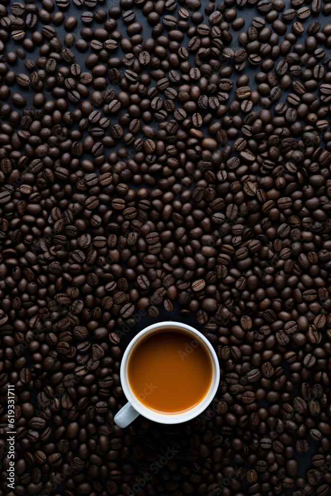 Coffee cup with coffee beans on dark coffee table.