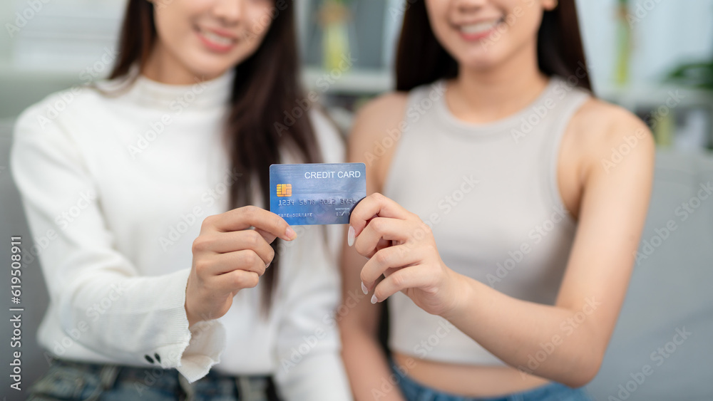 Close up hand of Two beautiful young women show their credit cards in the living room. The concept s