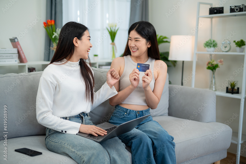 Two young Asian women delighted while using their credit card to make purchases. Successful online s