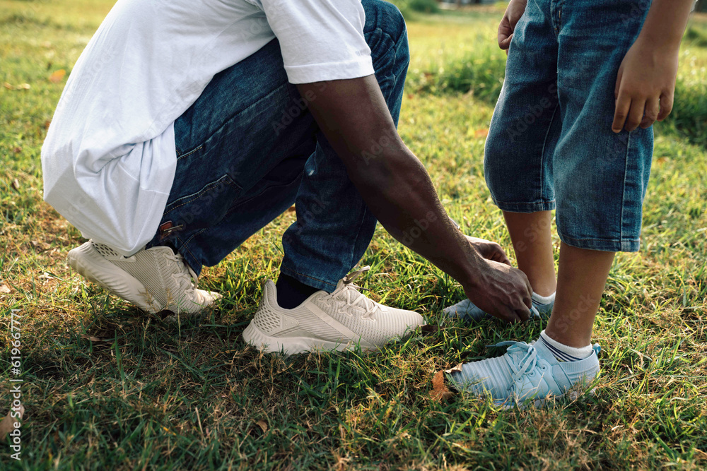 Warm Sunny Day in the Park: African American Father Assists Son in Tying Shoe Lace