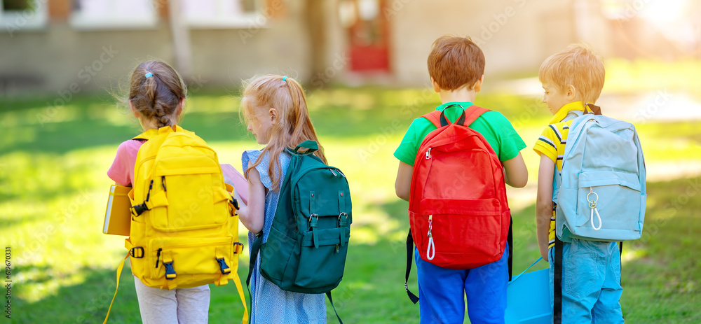 Group of children standing with backpacks near the school.