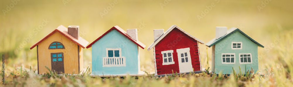 Four colourful models of houses standing on the lawn in natural park.