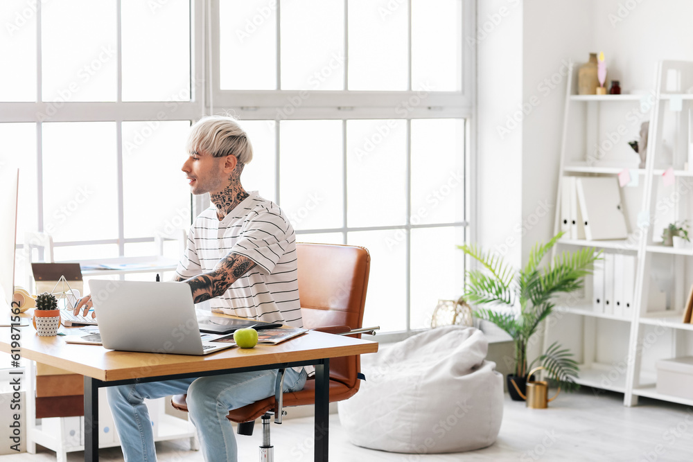 Tattooed graphic designer working with computer at table in office