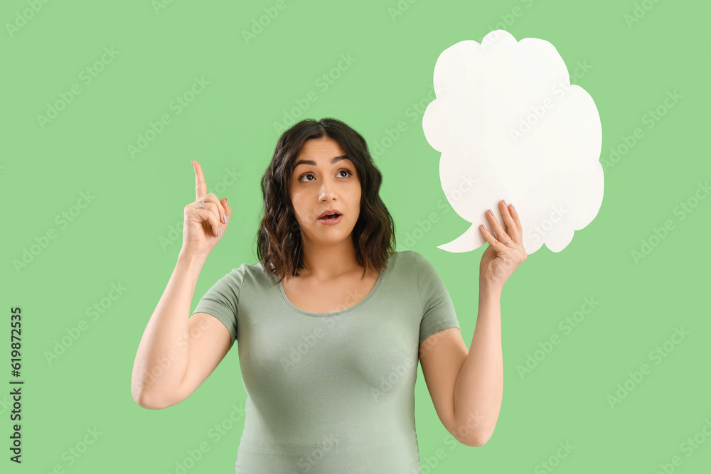 Young pregnant woman with blank speech bubble pointing at something on green background