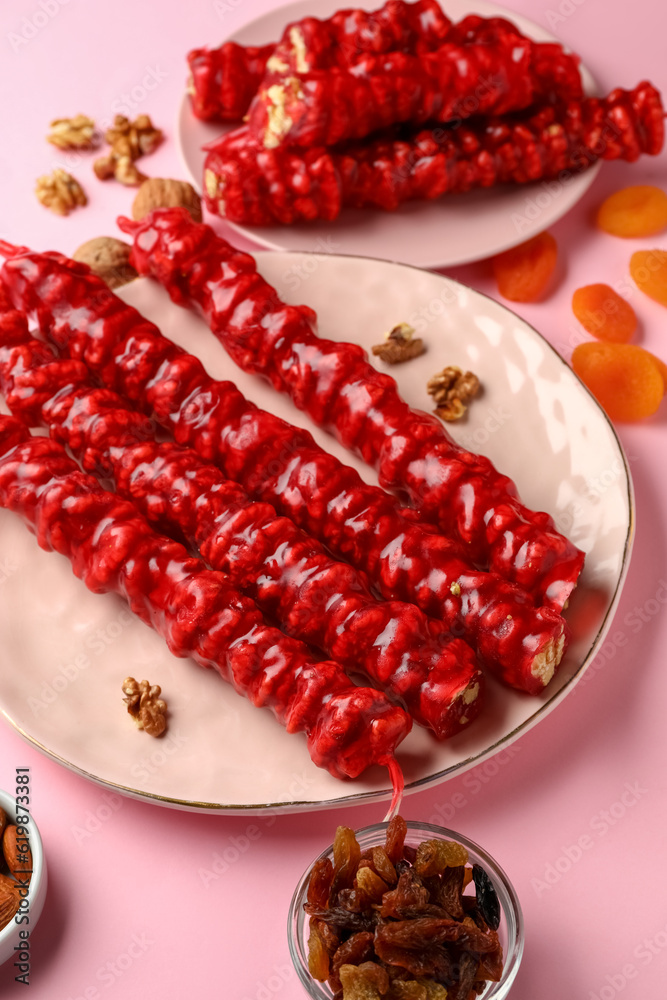 Plates with tasty churchkhela on pink background