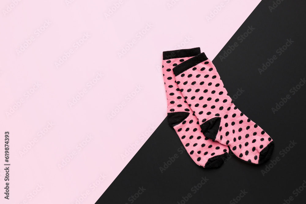 Pair of pink socks on color background