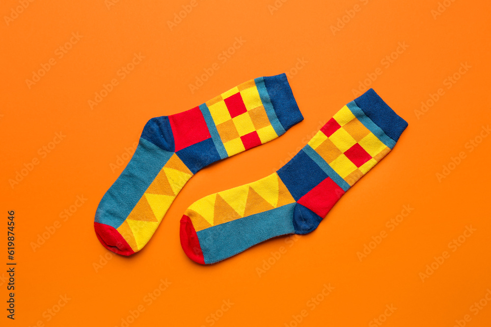 Pair of stylish socks on orange background