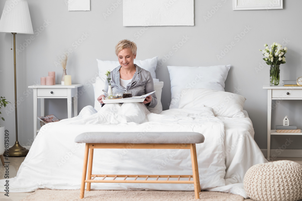 Mature woman having breakfast in bed