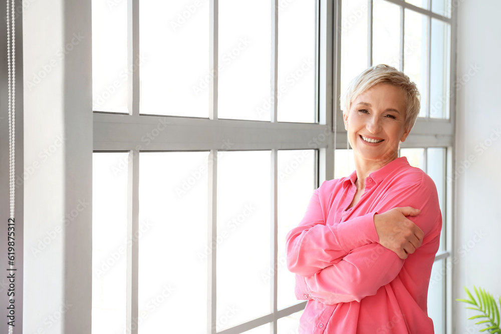 Happy mature woman near window at home