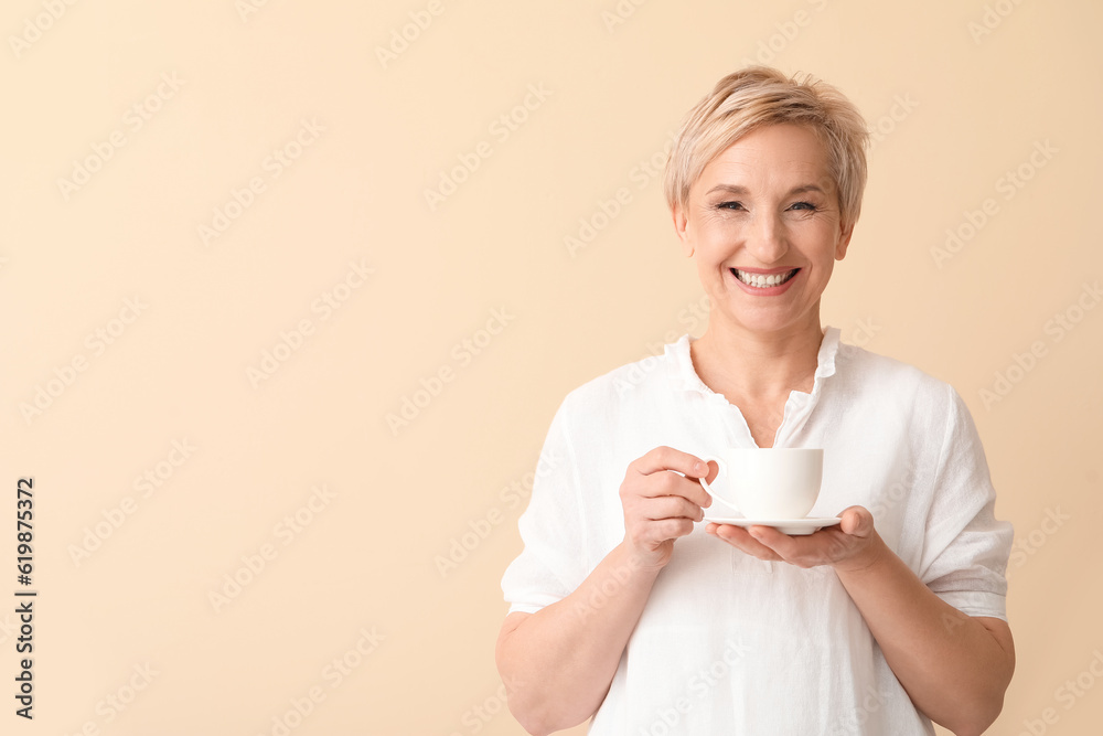 Mature woman with cup of coffee on beige background