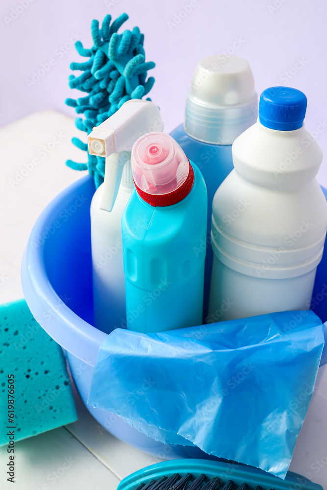 Bowl with different cleaning supplies on light wooden table, closeup