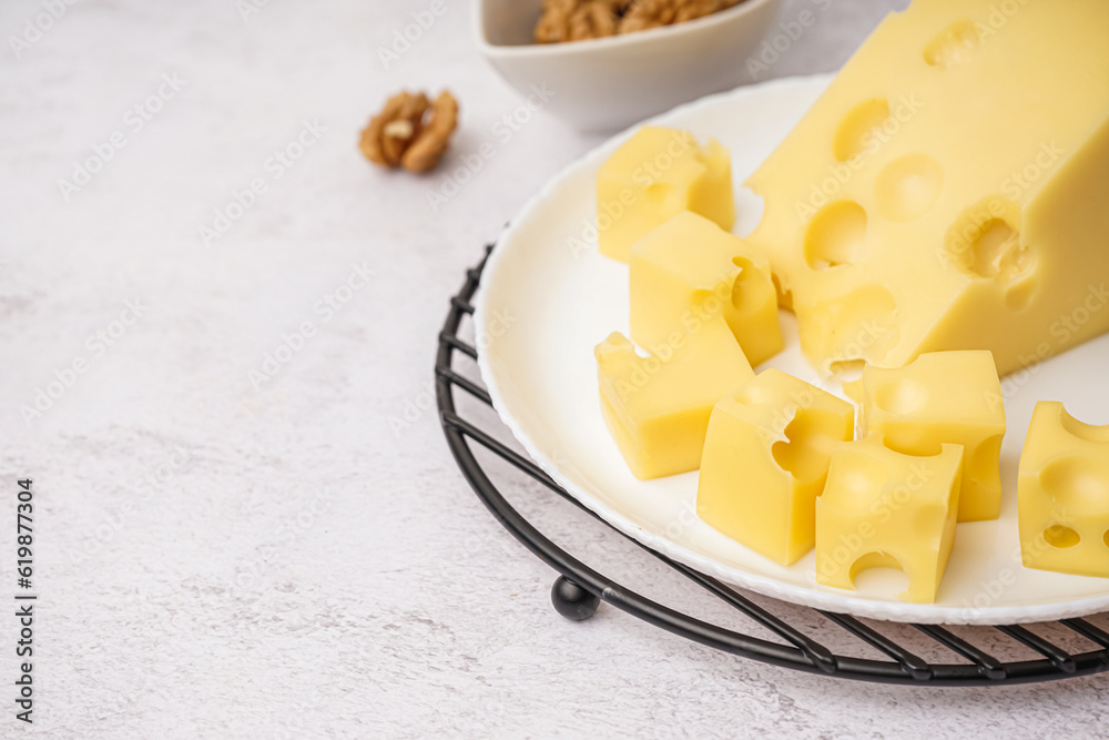 Stand and plate with pieces of Swiss cheese on white table